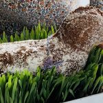 Kuchen in Lammform mit Puderzucker bedeckt in einem Pflanzentopf mit hohem Gras stehend